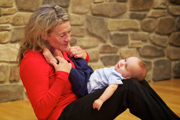 A woman stretching with a baby in her lap