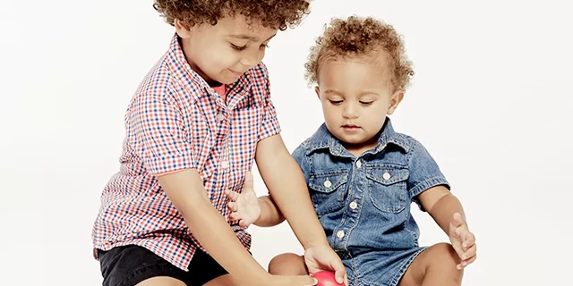 Siblings playing egg shakers together in Tam Tam's music class.