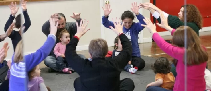 A class of children and grownups singing and waiving arms