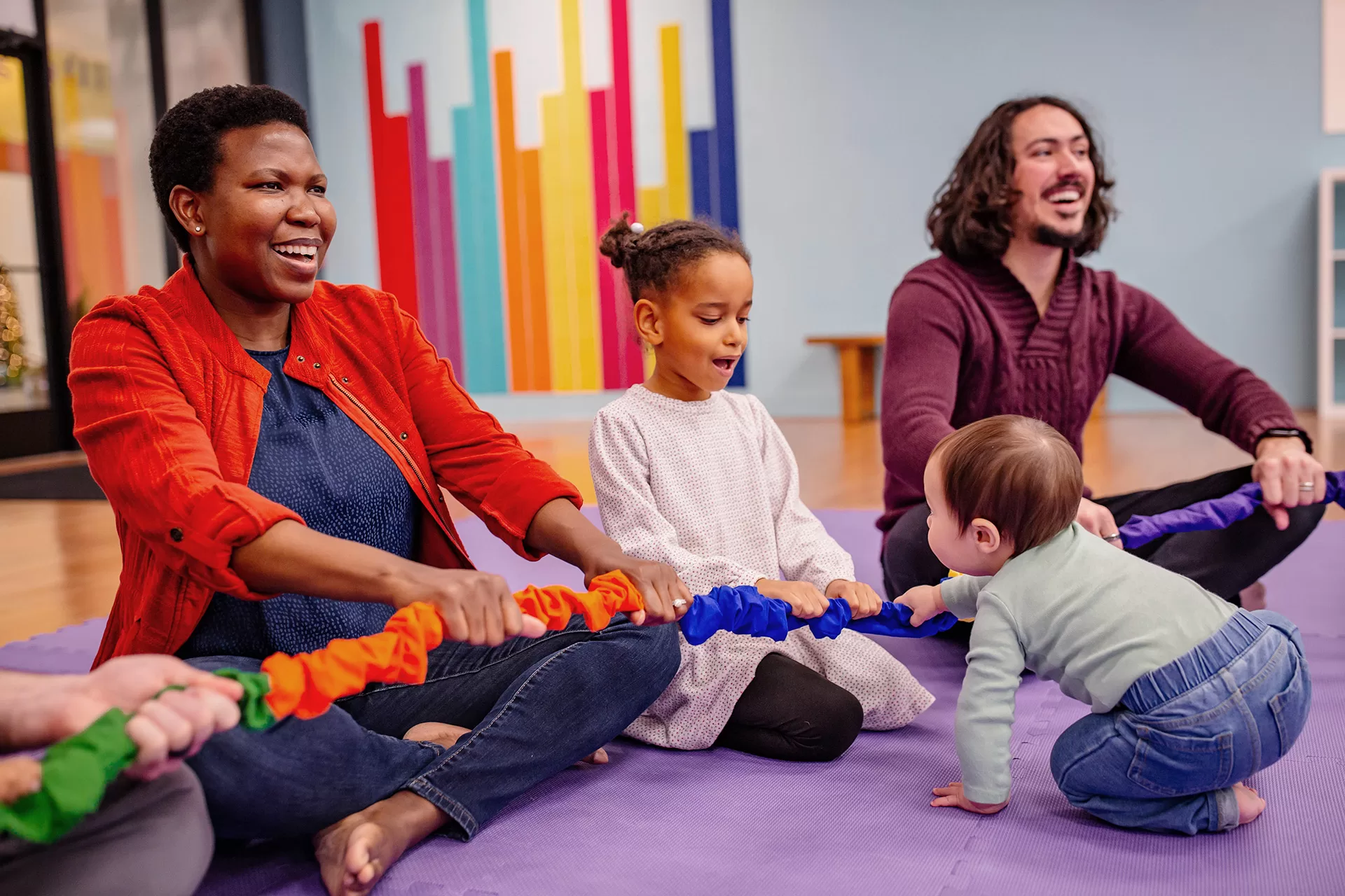 Two adults and two children singing and playing with the stretchy band
