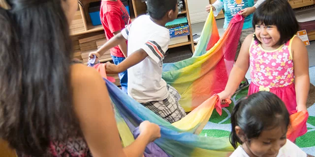 Preschool children dancing with scarves during a music and movement class supporting wellness and early childhood development.