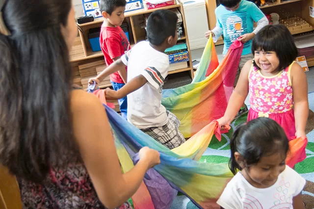 Preschool children dancing with scarves during a music and movement class supporting wellness and early childhood development.