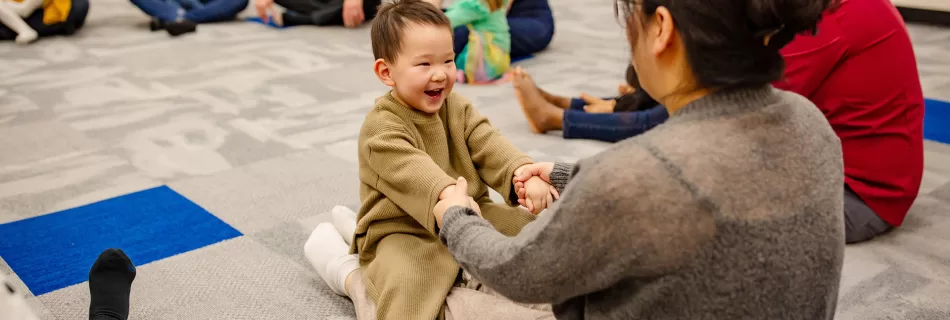 Child and mom holding hands and singing in Tam Tam's music class