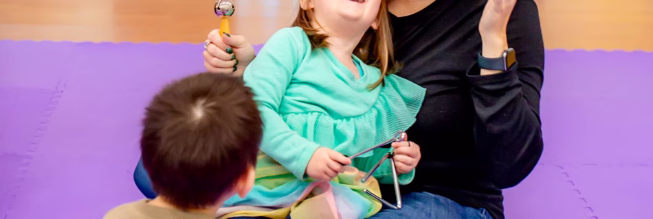 Two children and a mom playing with instruments in Tam Tam's music class