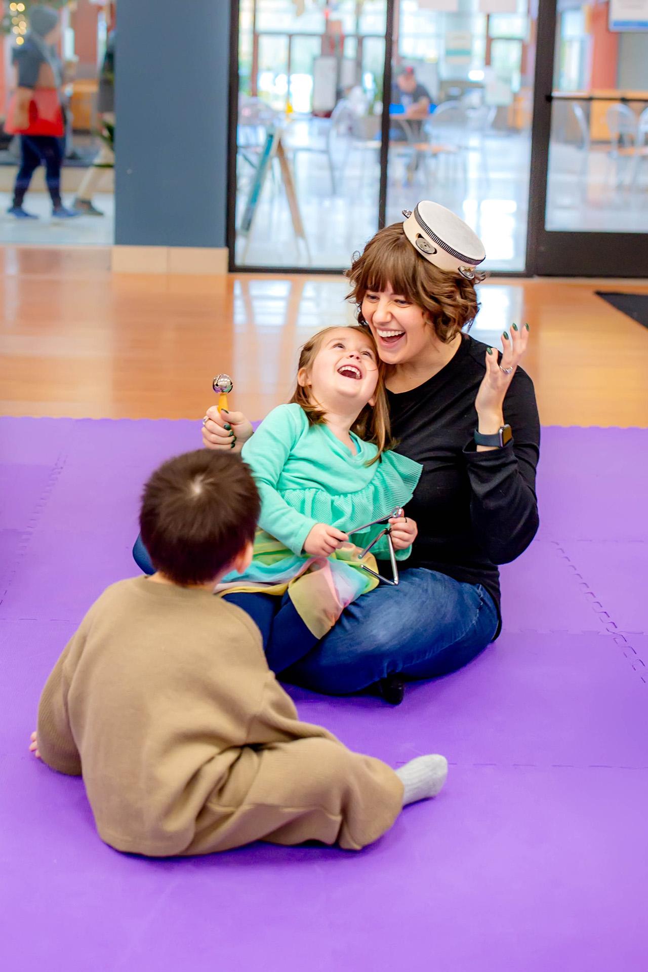 Two children and a mom playing with instruments in Tam Tam's music class