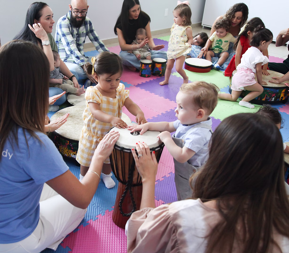 Toddlers and grownups drumming in music class